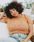 A peach t-shirt with text on the front that reads, "The Future is Inclusive.".