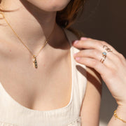 A model wearing a gold necklace with 3 stones on it.