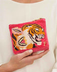 A hot pink velvet pouch with a tiger and floral design and a zipper closure.