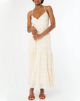 On a white background is a natural colored lace dress with spaghetti straps and a cross cross back.