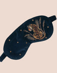 A dark blue sleeping eye mask with a tiger embroidery on the front.