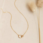 A dainty gold chain necklace with two different sized circle links connecting in the center.