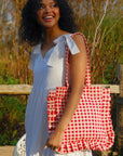 A red and white gingham printed tote bag with shoulder straps and a ruffle edge detail.