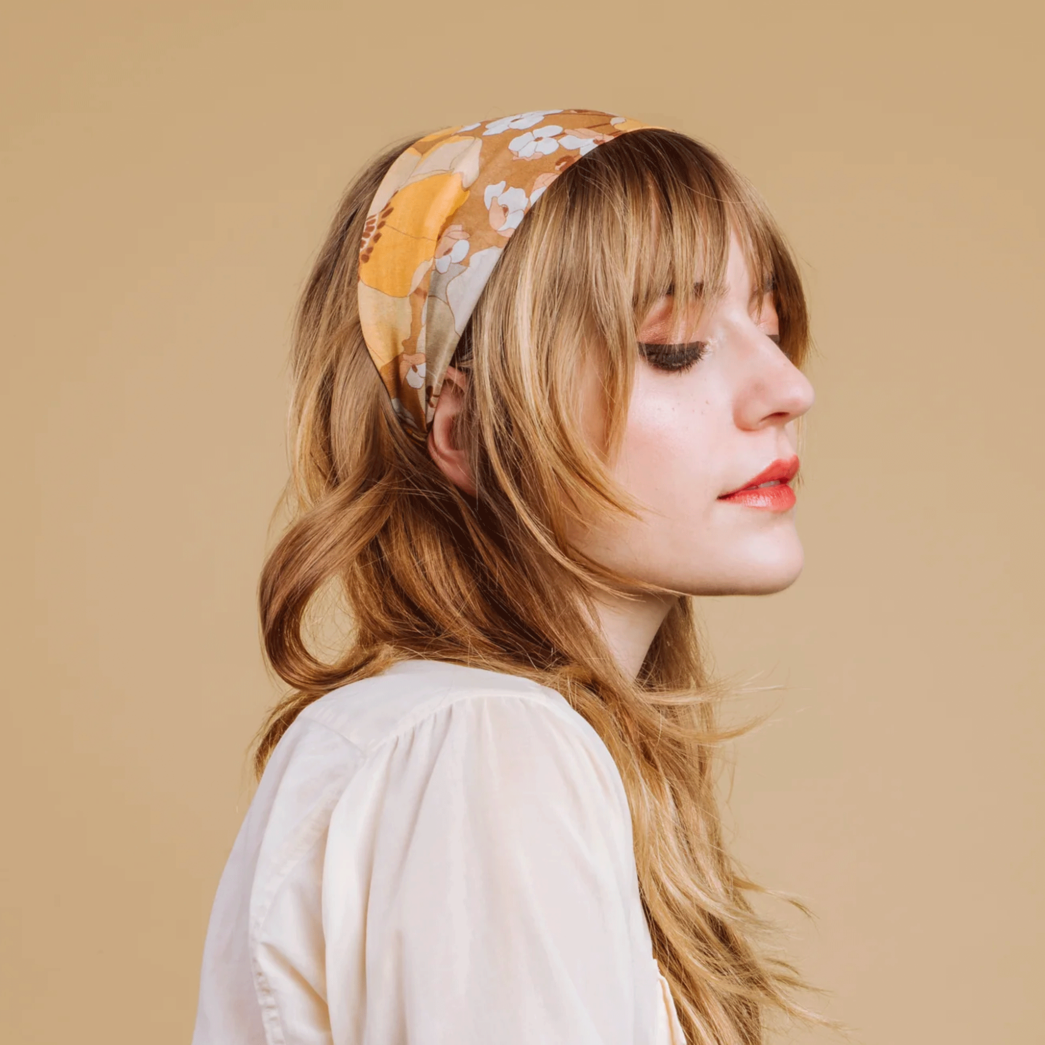 A model wearing a wide headband with an ivory and yellow floral print. 