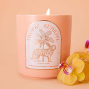A light peach colored candle with a tiger and palm tree graphic and text above that reads, 'Tropic Sunrise'.