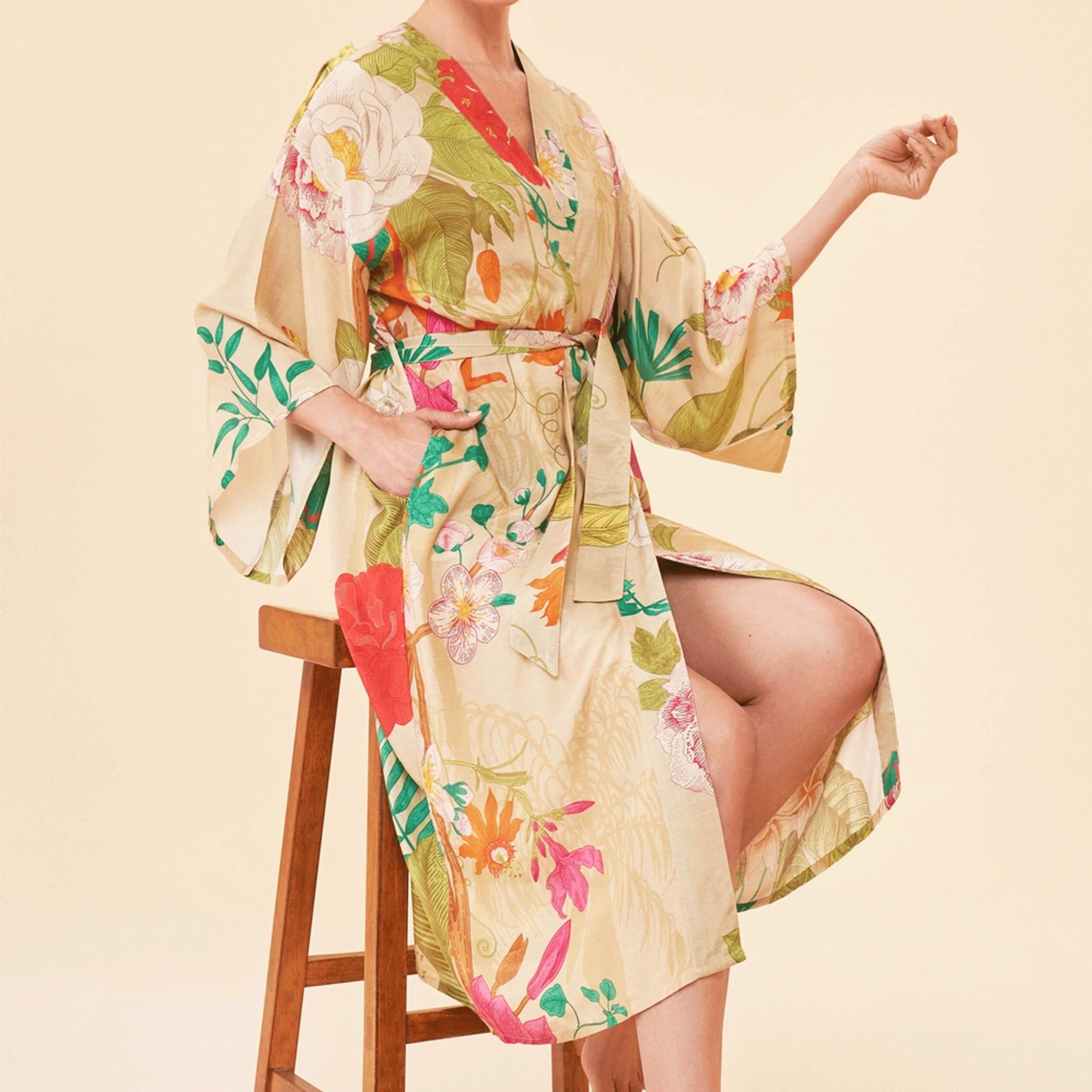On a tan background is a model wearing a tan robe with a multicolored floral print.  
