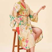 On a tan background is a model wearing a tan robe with a multicolored floral print.