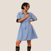 A light blue utility dress with short sleeves, collars and a white stitching.