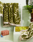 A green and ivory bamboo printed bath towel with tassel ends on both sides.