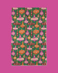 On a pink background is a green towel with a multi color ornament pattern.