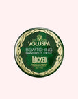 A green tin candle with gold details that reads, 'Voluspa, Bewitching Banyan Forest' Wicked.