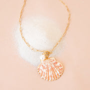 A gold chain necklace with a shell shaped pendant hanging from the center.
