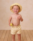 A yellow pair of boardshorts for kids with a textured wave pattern.