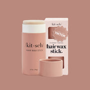 A mauvy cardboard packaging with a wax hair stick inside with black text that reads, 'kit-sch Hair Wax Stick'.