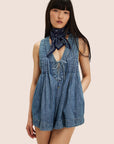 A model wearing a short denim romper with a v-neck and string tie in the center.