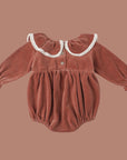 A cranberry colored velvet romper with a white lace ruffle neckline and sleeve.