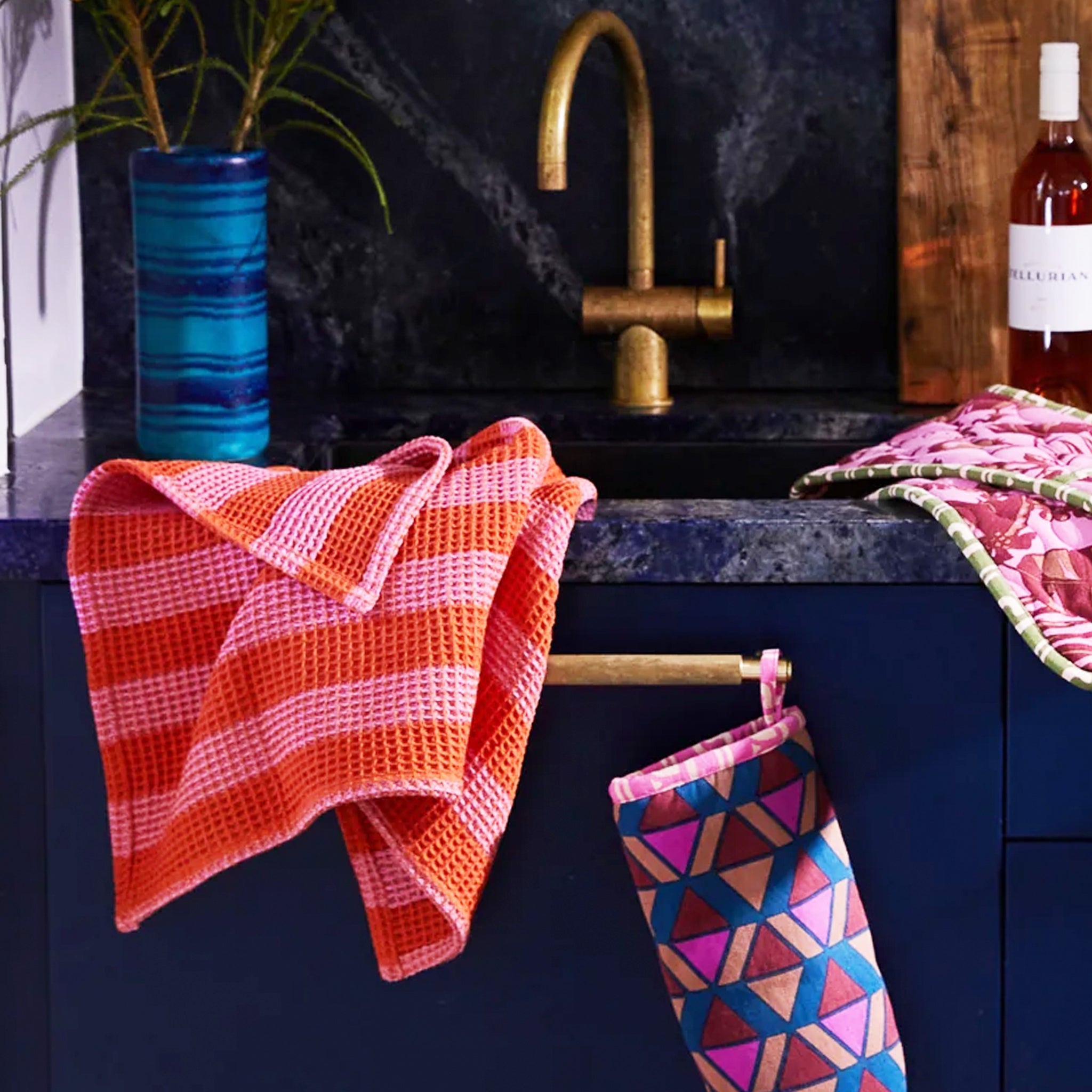 A pink and orange striped waffle knit tea towel with a convenient loop for hanging.