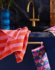 A pink and orange striped waffle knit tea towel with a convenient loop for hanging.