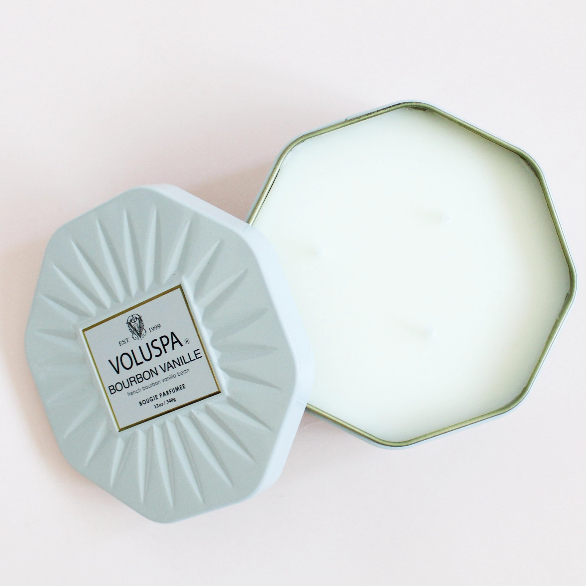 birds eye view of a white octagon shaped candle lies open with the lid off to the side. the lid reads voluspa bourbon vanille. french bourbon vanilla bean scent.