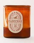 Oval cylinder shaped glass candle with bright tones of burnt orange. The label is an oval shape and reads 'Tobacco & Patchouli' with a galloping horse image within. The middle reads 'PaddyWax Since Ninety Six: Nashville, Tennessee'.