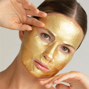 A gold sheet face mask being modeled and has cut outs for the mouth, nose and eyes.