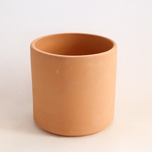 On a white background is a terracotta cylinder planter with a raw terracotta finish. 