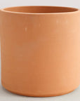 On a white background is a terracotta cylinder planter with a raw terracotta finish.