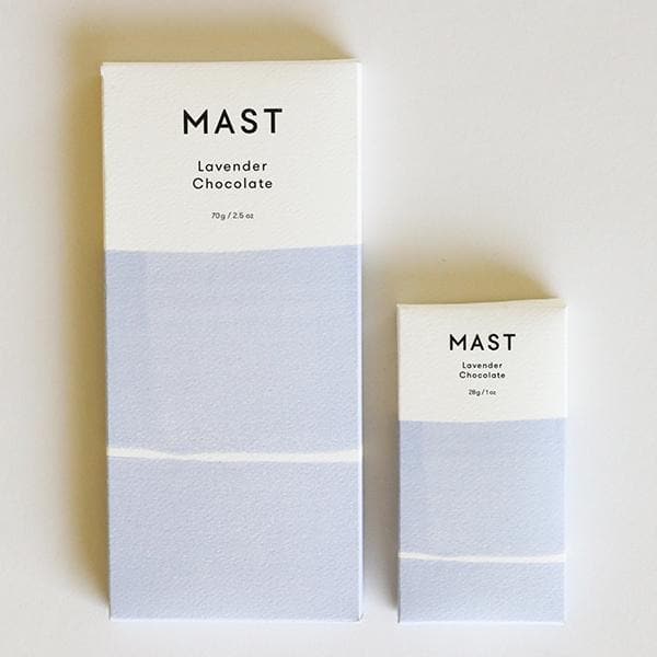 Two different sized chocolate bars with white and light purple packaging along with black letters at the top that read, "Mast Lavender Chocolate".