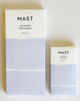 Two different sized chocolate bars with white and light purple packaging along with black letters at the top that read, "Mast Lavender Chocolate".
