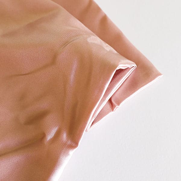 This is a close up picture of folded fabric. The fabric is blush pink. 