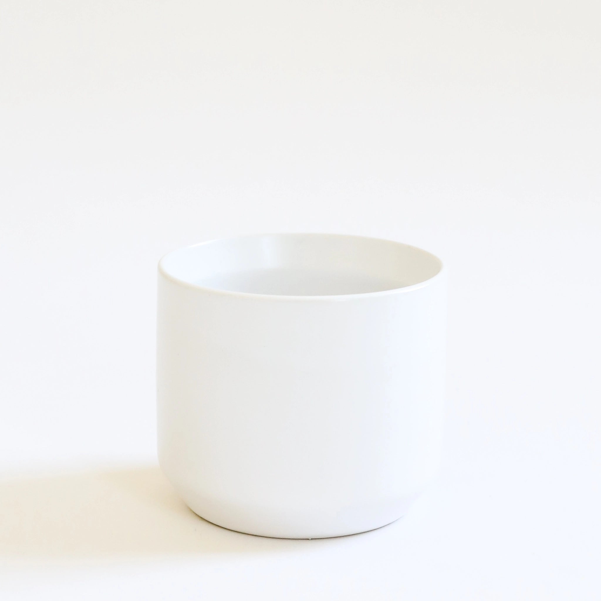 empty simple white pot sits on a white ground