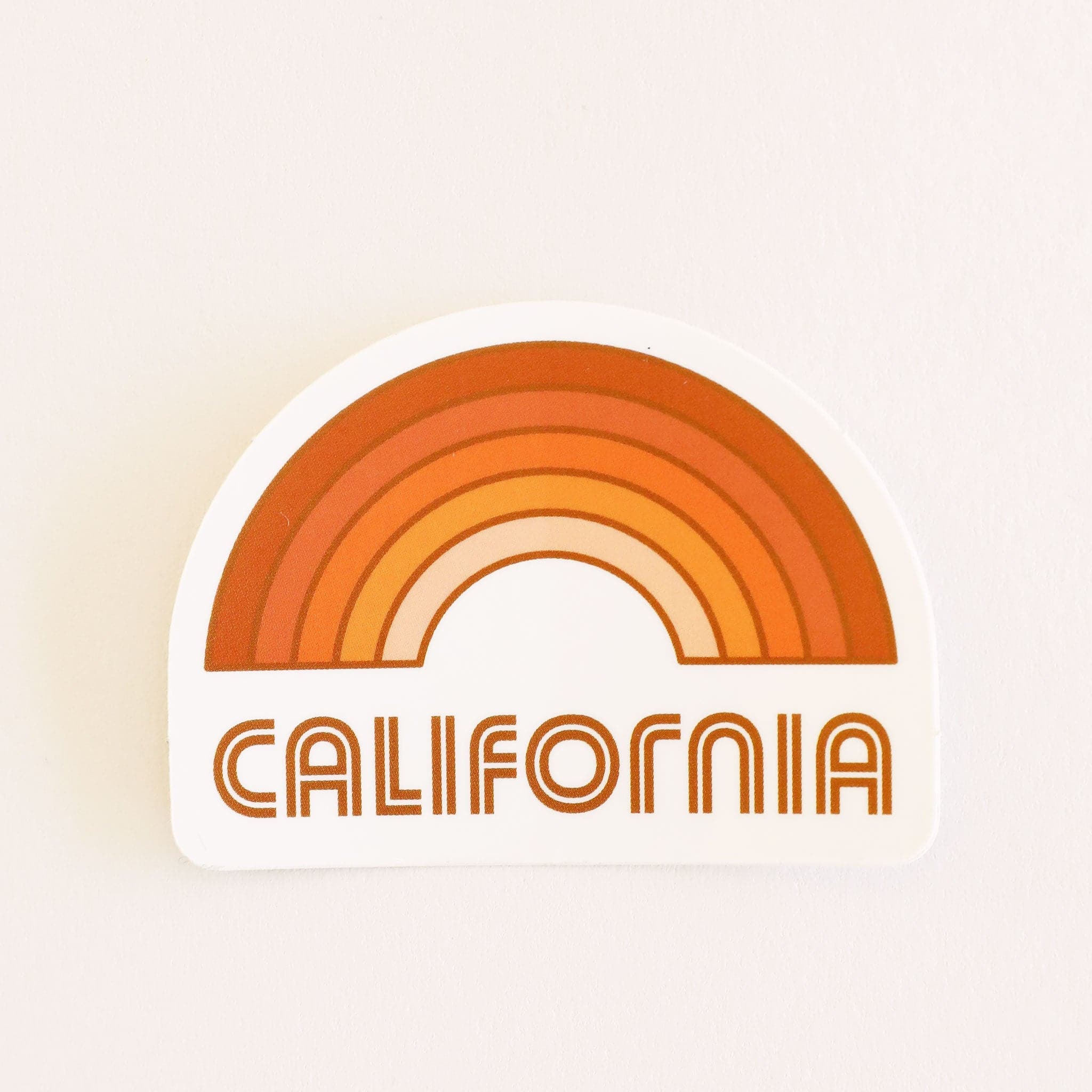 A rainbow sticker made up of different shades of orange and &quot;California&quot; written in orange letters on the bottom underneath the rainbow graphic.