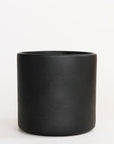 On a cream background is a matte black cylinder planter with a smooth cylinder shape.