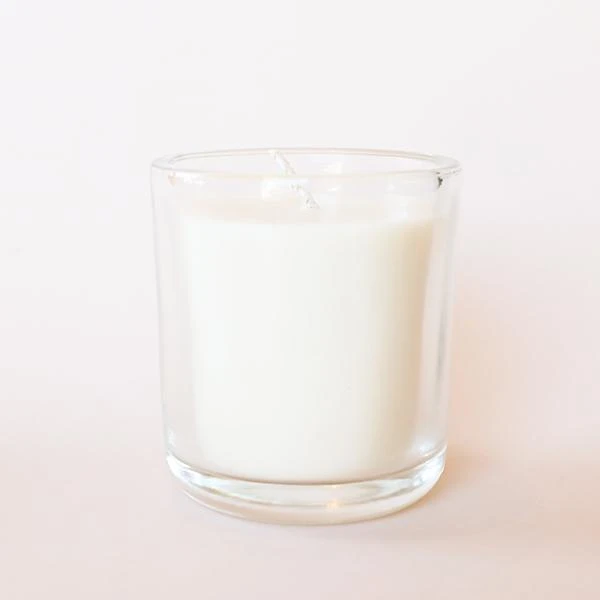 Coconut Milk Candle - Pigment A clear glass jar candle with white wax and a white square label that reads, &quot;Coconut Milk Makana&quot; in clean black text.