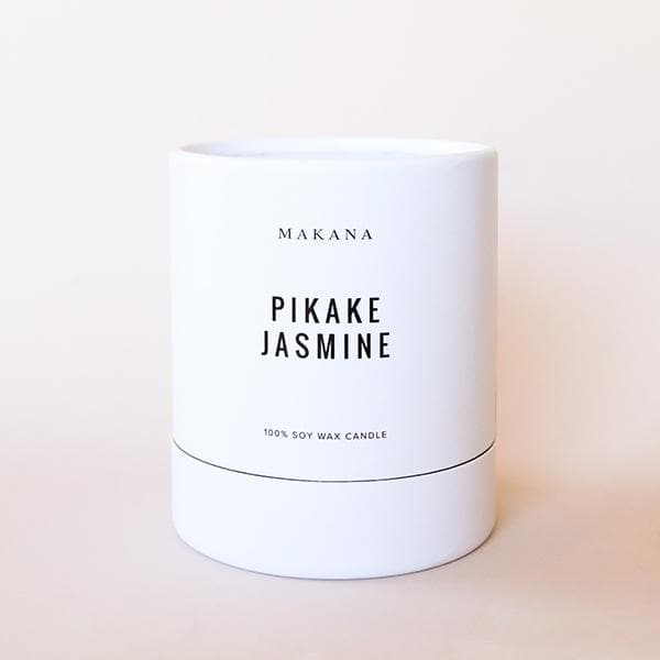 In front of a white background is a white round package. On the front is black text that reads ‘Makana, Pikake Jasmine.&#39;