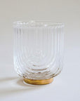 A clear glass tumbler with a gold base and an etched upside down arched design.