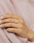 On a model's finger is a thin heart shaped ring with the center left open.