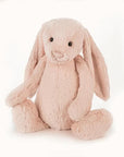 Soft stuffed animal in the shape of a pink blush colored rabbit with long floppy ears, arms and legs.