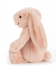 Soft stuffed animal in the shape of a pink blush colored rabbit with long floppy ears, arms and legs.