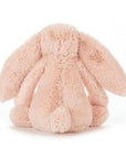 Soft stuffed animal in the shape of a pink blush colored rabbit with long floppy ears, arms and legs.