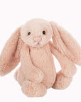 Soft stuffed animal in the shape of a pink blush colored rabbit with long floppy ears, arms and legs.