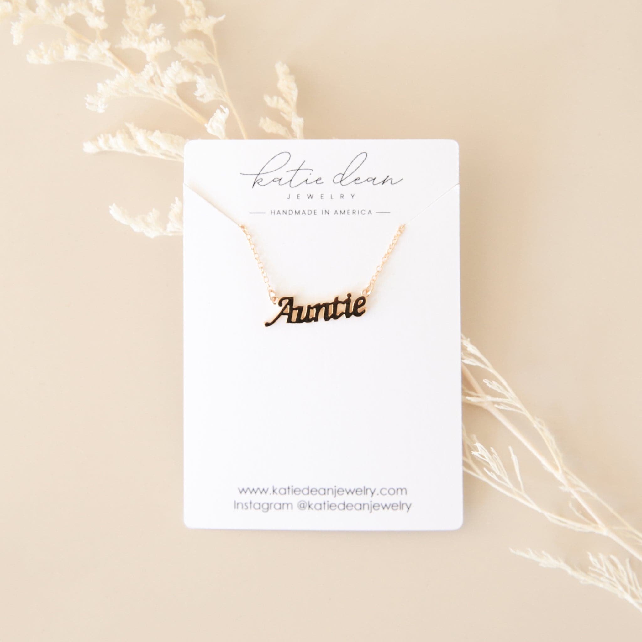 &quot;Katie Dear Jewelry&quot; white card with gold necklace in the shape of the word &quot;Auntie&quot;