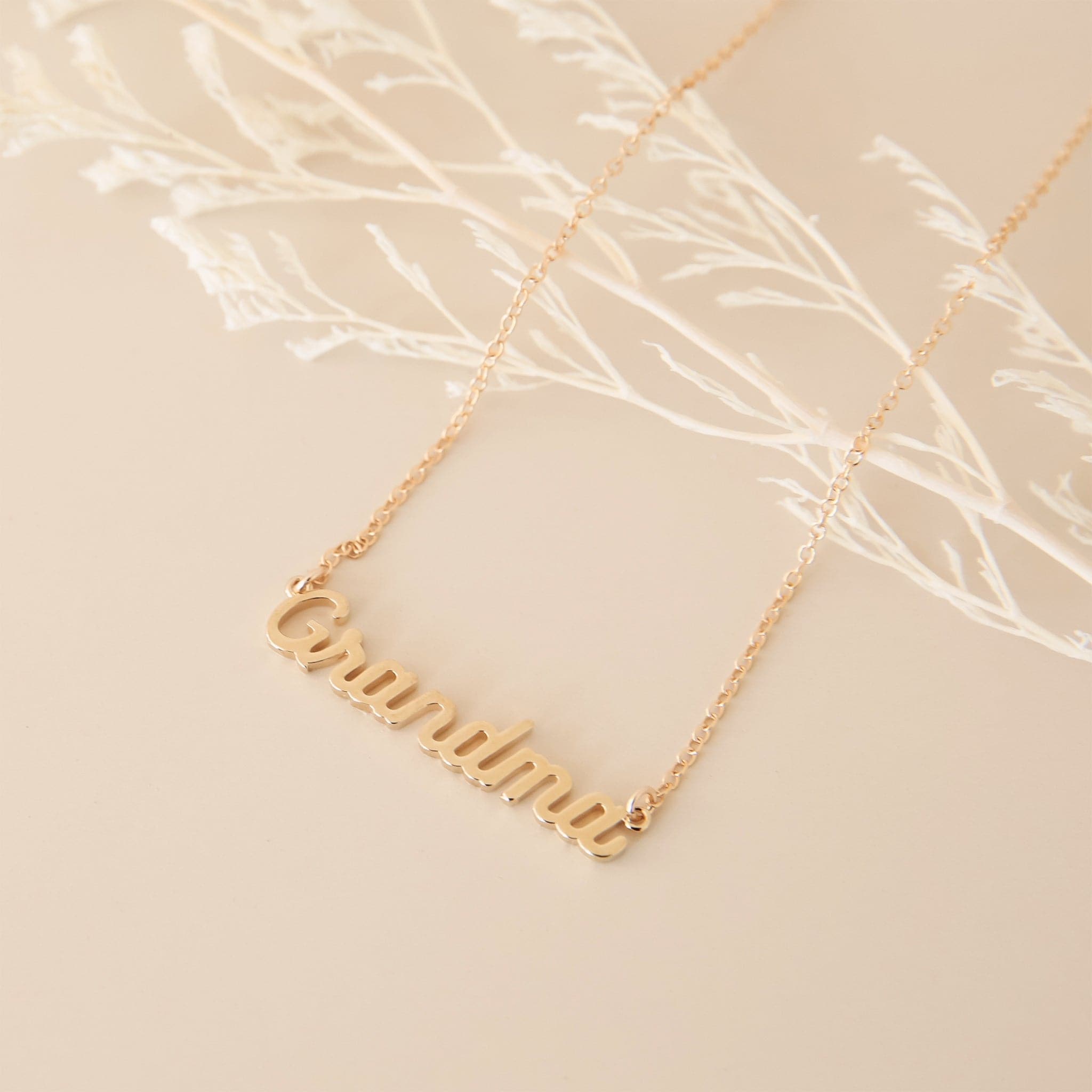 A dainty gold chain necklace with gold letters that read, &quot;Grandma&quot; as a pendant.