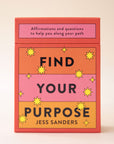 An orange, yellow and pink deck of cards with the words, "Find Your Purpose" on the front as well as "Affirmations and questions to help you along your path" in black writing.