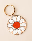 Circle flower keychain with white petals and red-orange center. The keychain is complete with a golden key chain ring.