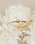 On a cream background is a dainty gold ring with an "B" in the center.
