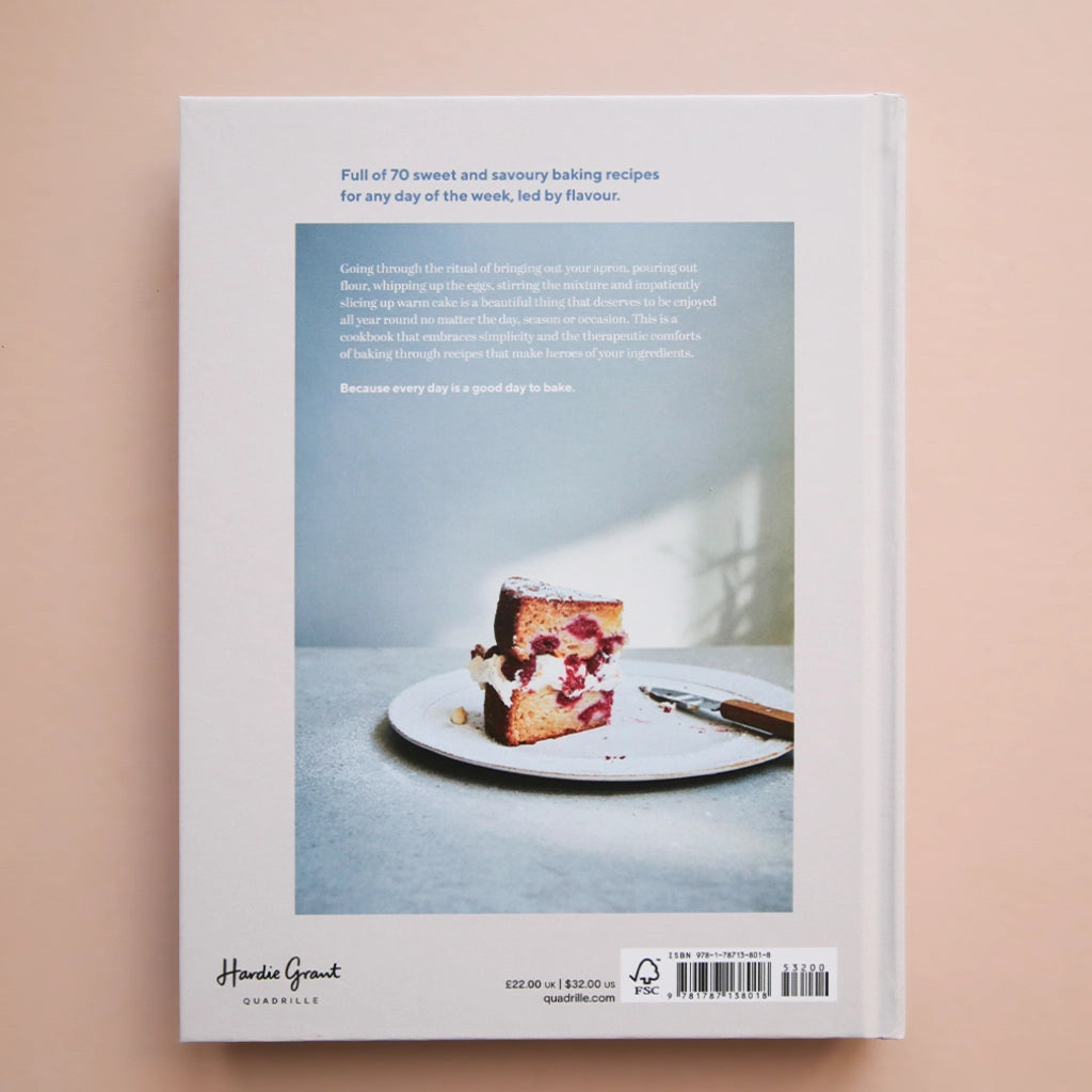 A white book cover with a photograph of a chocolate cake being cut along with the title that says, &quot;a good day to bake&quot; in light blue font.