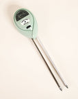 A light blue moisture meter with a circular head and a meter with a black background and text in the center that reads, "Three-way Meter" in black writing along with two long metal points that are meant to go into your plant's soil to determine the moisture levels.