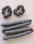 A black satin heatless curler with two included scrunchies.