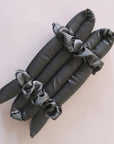 A black satin heatless curler with two included scrunchies.